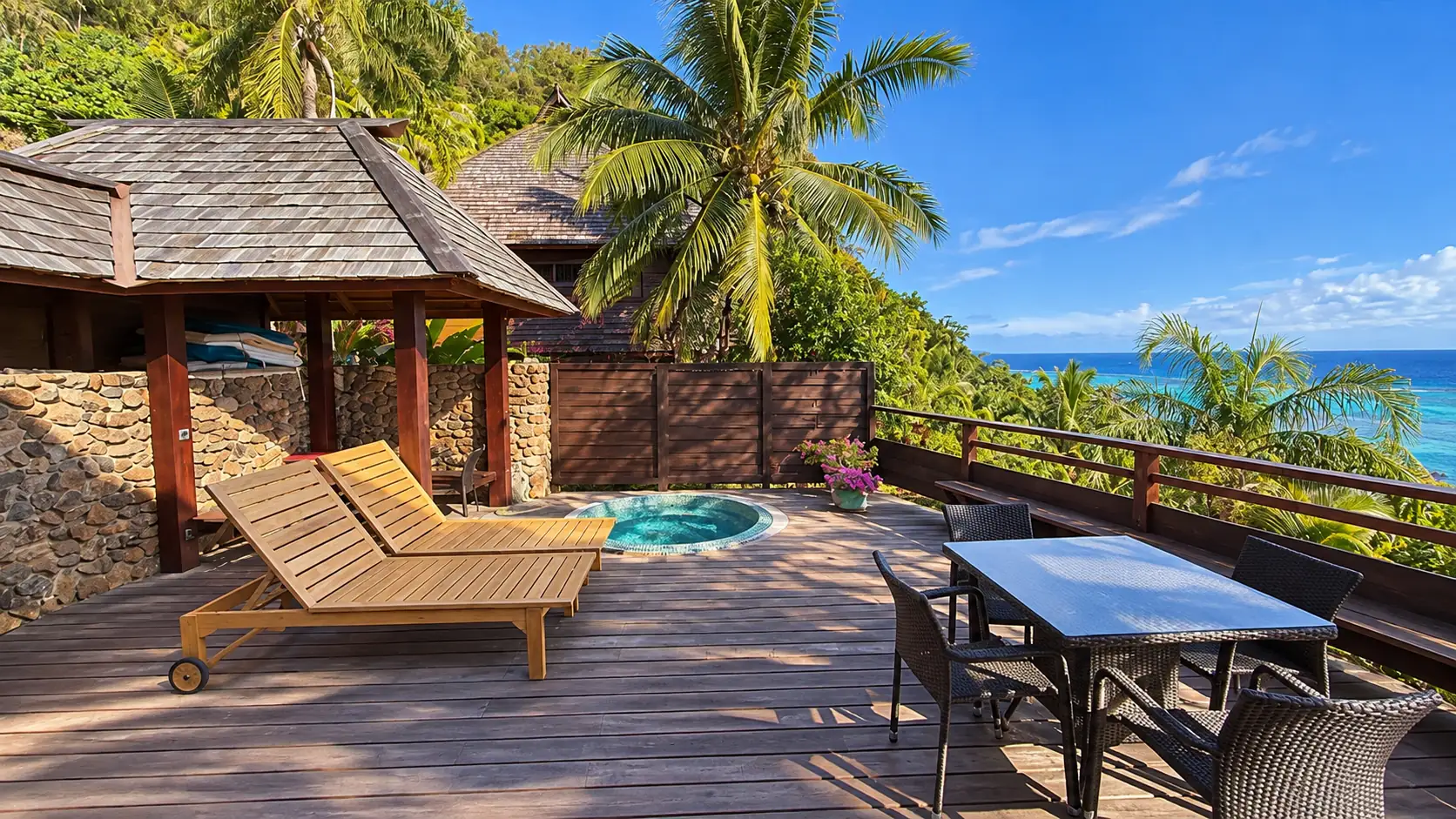 Terrasse avec bain à remous, transats en bois et table face à l'océan